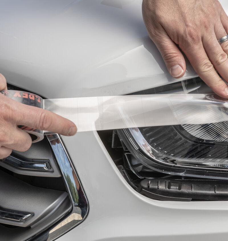 A car headlight being repaired using T-Rex Clear Repair Tape