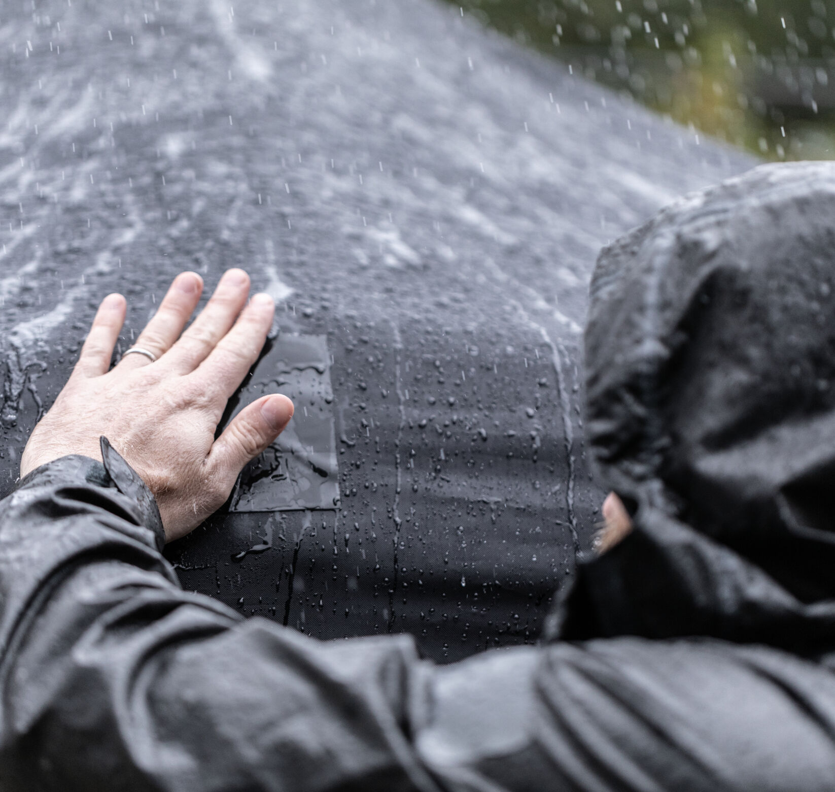 A man repairing a tarp with T-Rex Tape in the rain