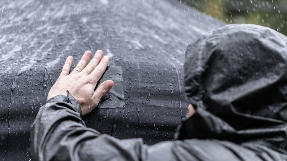 A man repairing a tarp with T-Rex Tape in the rain