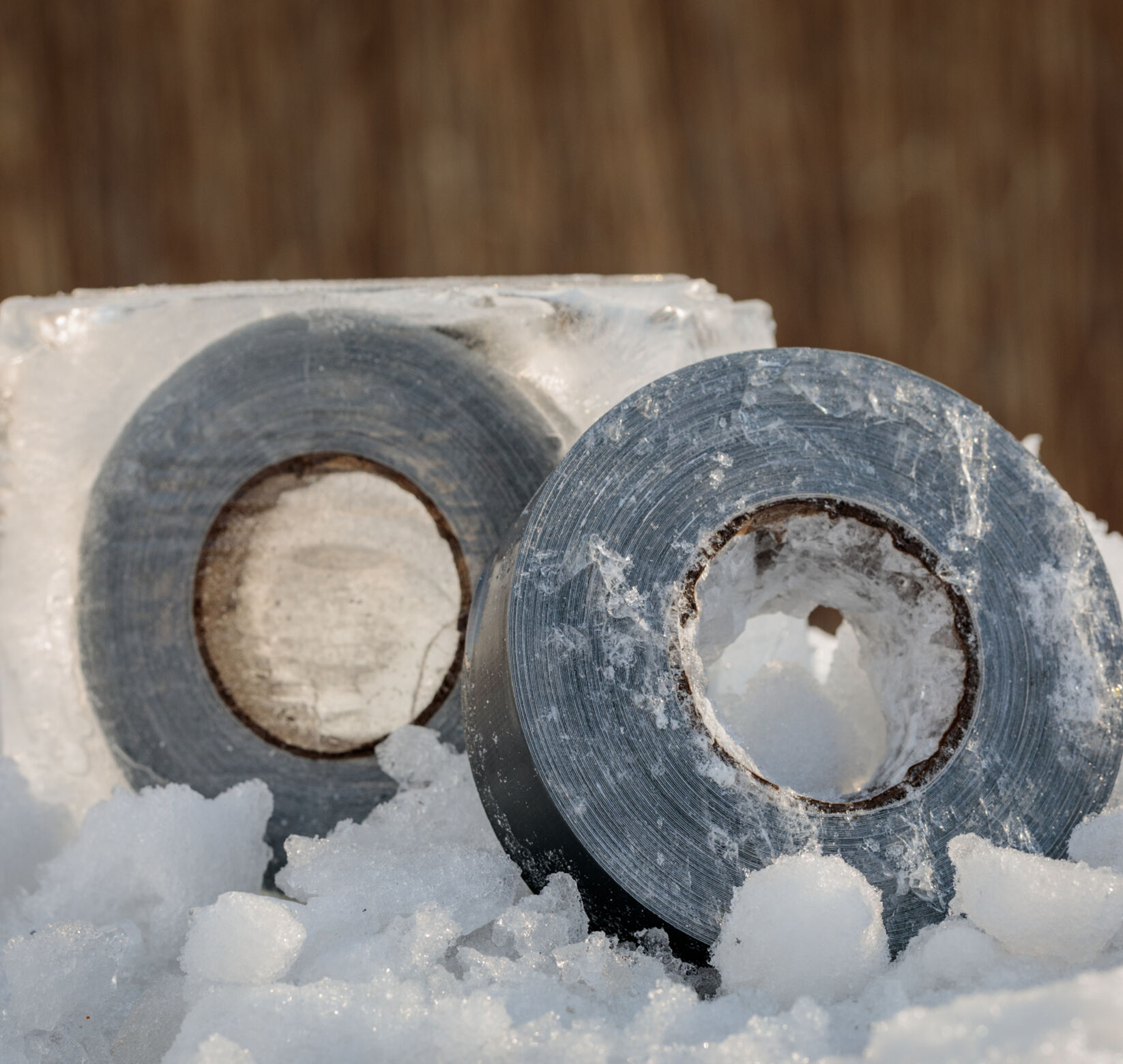 Two Rolls of T-Rex Duct Tape in the snow. One of them is frozen in a block of ice.