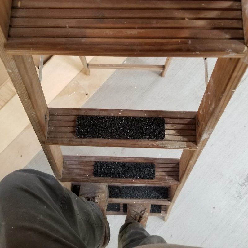 Man standing on a ladder with tread tape on the rungs